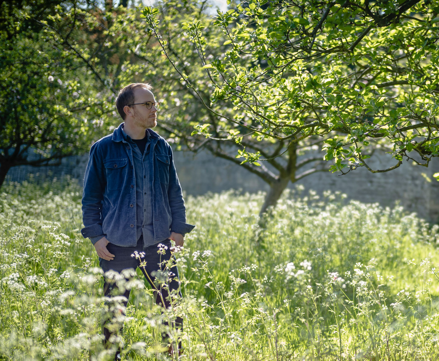Portrait of Colm Joseph Gardens founder and lead designer, Colm Joseph standing in an orchard and wildflower meadow 
